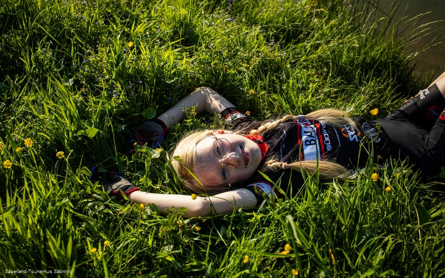 Mädchen liegt im Gras bei der Bike-Rast 