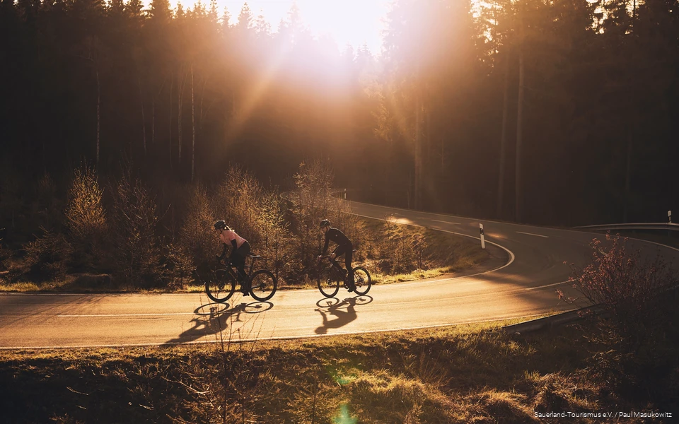 2 Rennradfahrende fahren im Sonnenuntergang