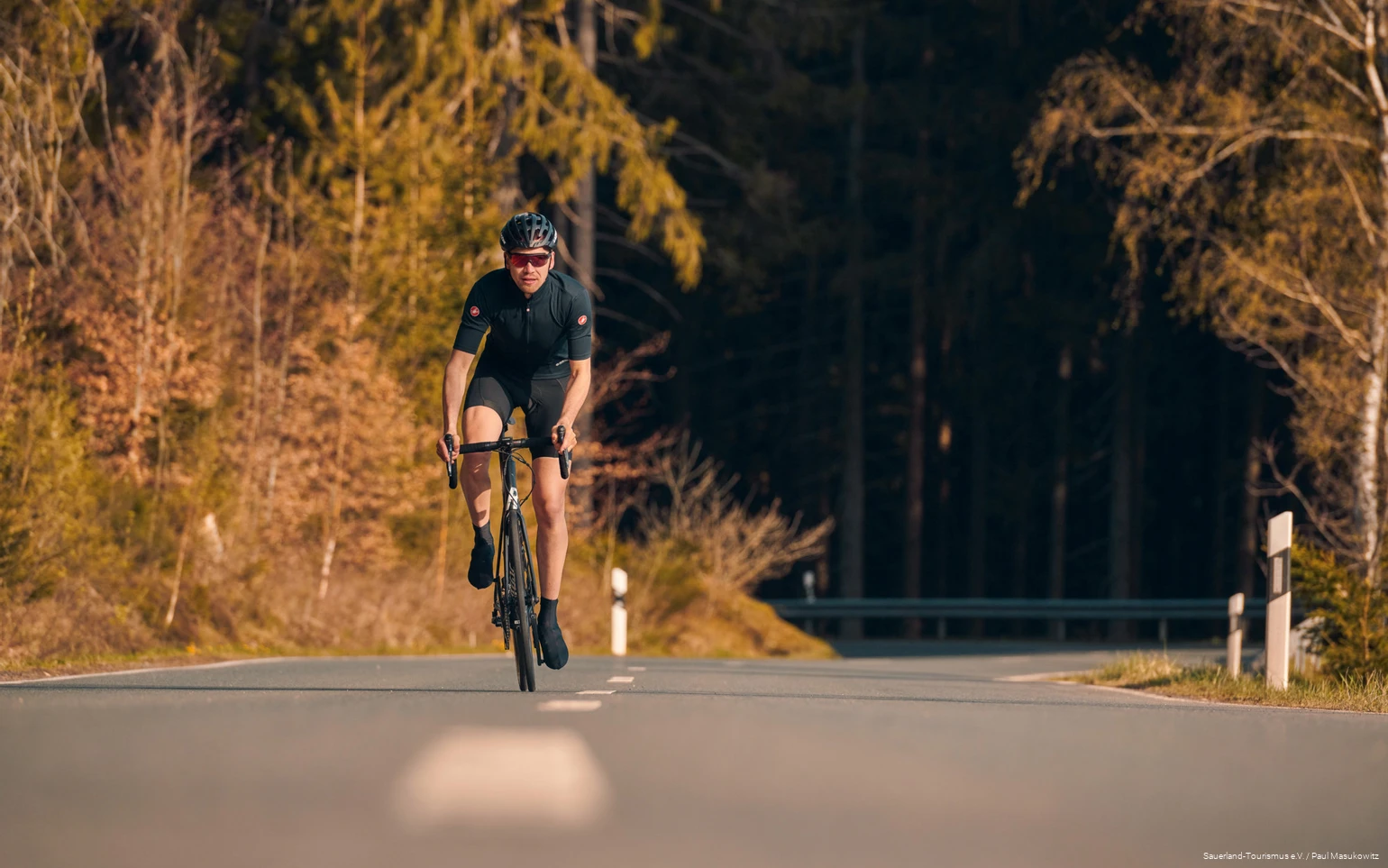 Rennradfahrer fährt im Wiegeschritt eine Straße hinauf